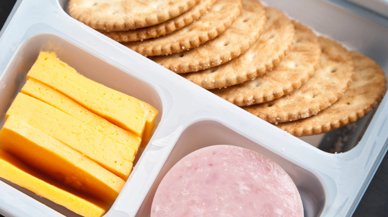 Crackers, sliced cheese and ham in a plastic tray